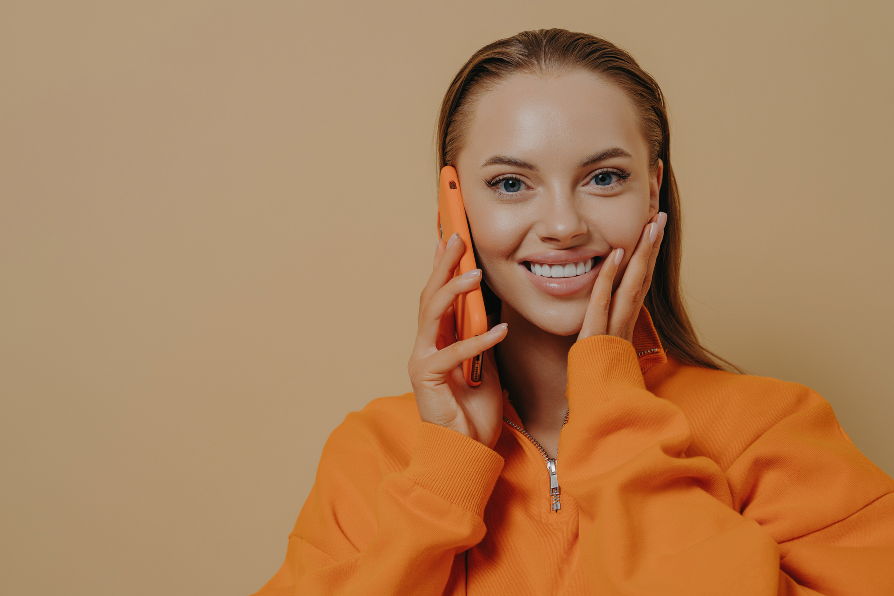 Happy Excited Woman Talking on Phone, Hearing Good News via Mobile Phone, Isolated over Beige Wall